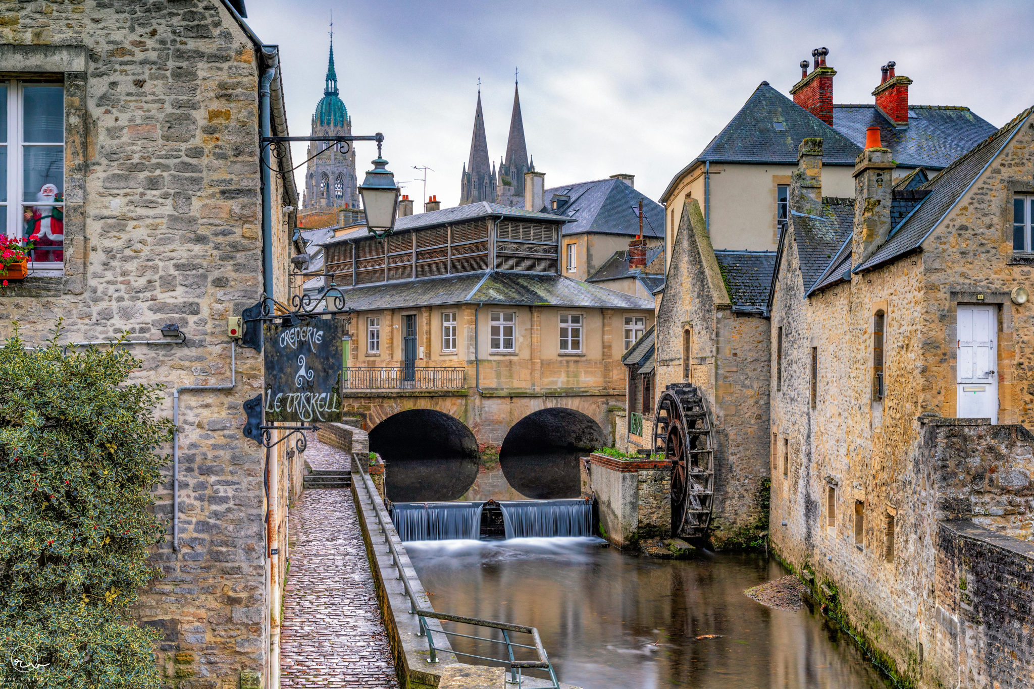 `Ruelle historique de Bayeux en Normandie, avec ses maisons en pierre et un pont sur la rivière Aure.