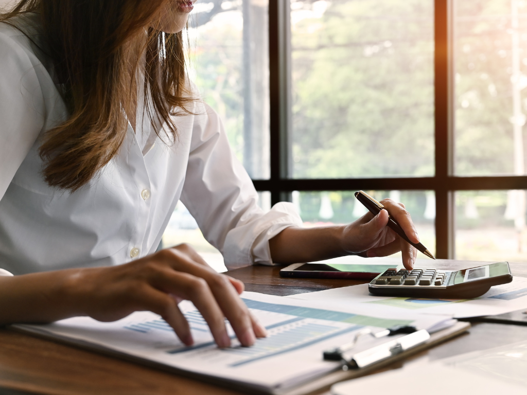 Une femme utilisant une calculatrice et étudiant des documents financiers pour un projet de construction.